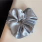Pink satin scrunchie embellished with rhinestones laid flat on a wooden surface