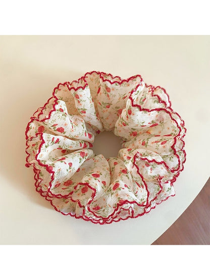 Red scrunchie with small white flowers displayed on a white background