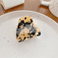 Small crescent claw clip with multicolor pattern shown against a neutral background