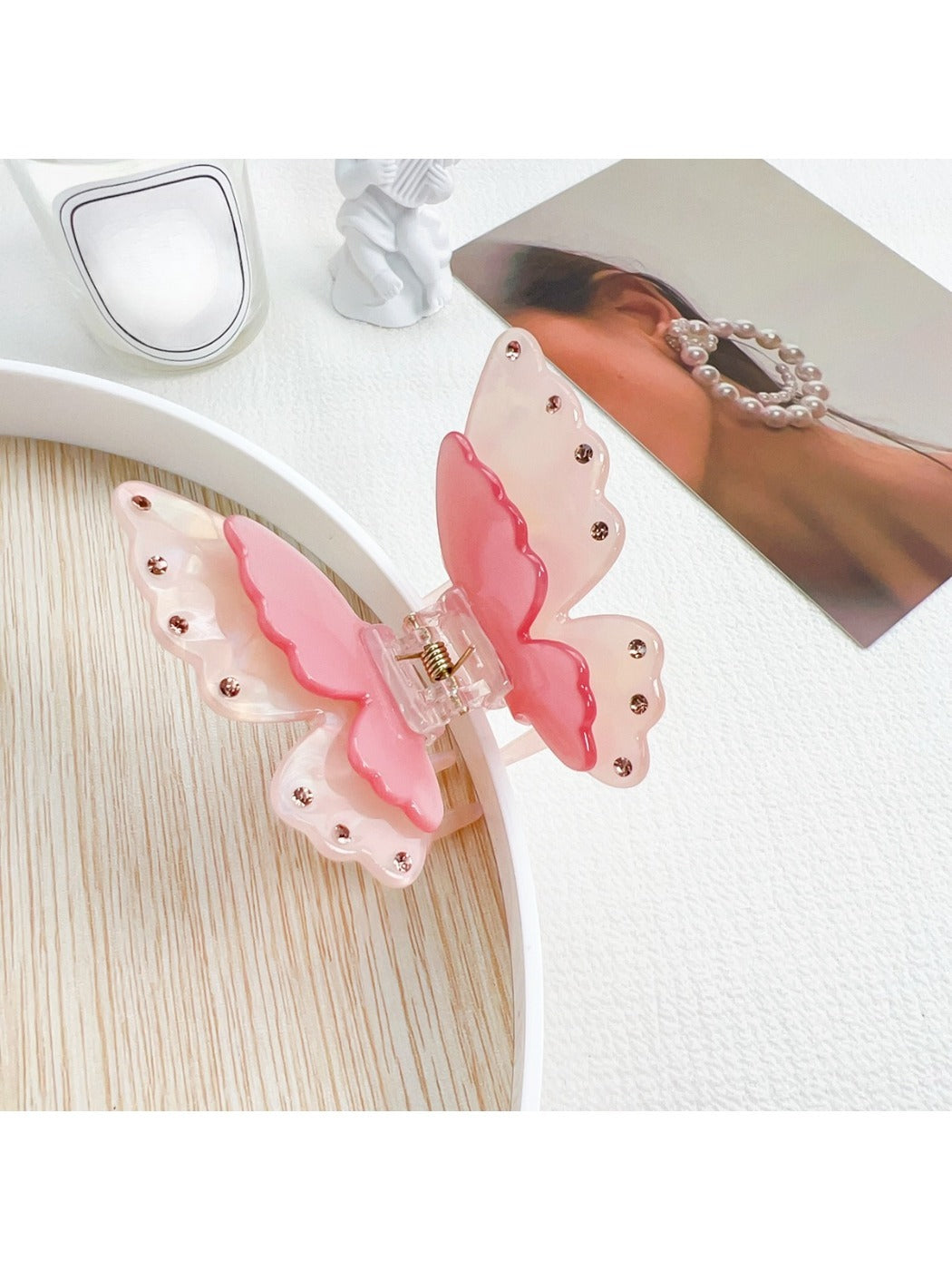 Pastel pink butterfly claw clip held in hand showing size and scale