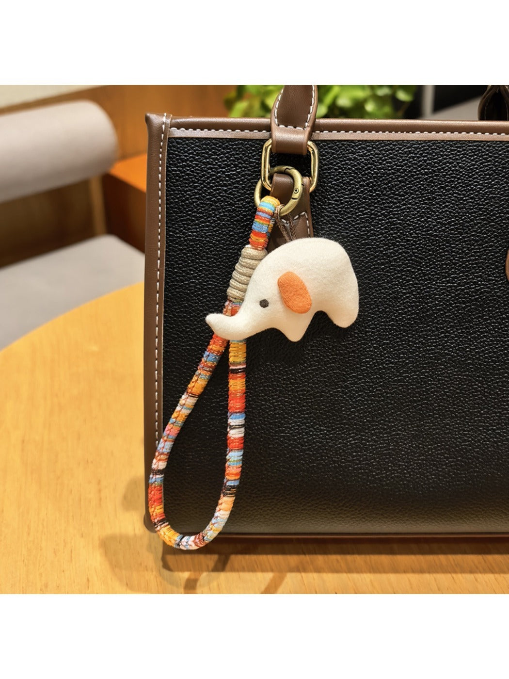 Elephant charm keychain held in a hand showing size comparison
