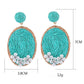 Earedge raffia woven oval earrings displayed hanging on a white stand