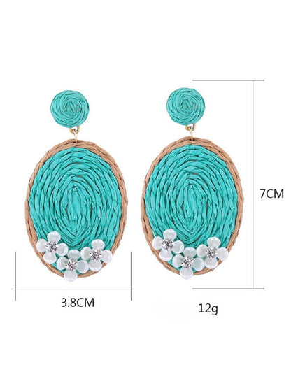 Earedge raffia woven oval earrings displayed hanging on a white stand