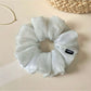 Side view of the grey scrunchie highlighting its elastic stretch and ruched design