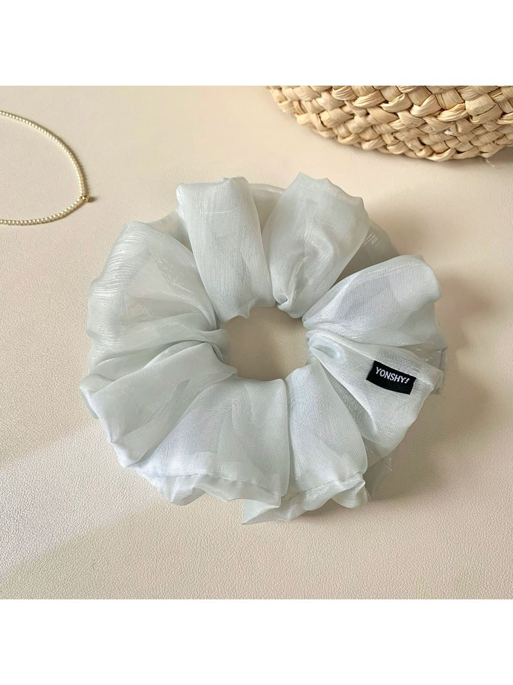 Side view of the grey scrunchie highlighting its elastic stretch and ruched design