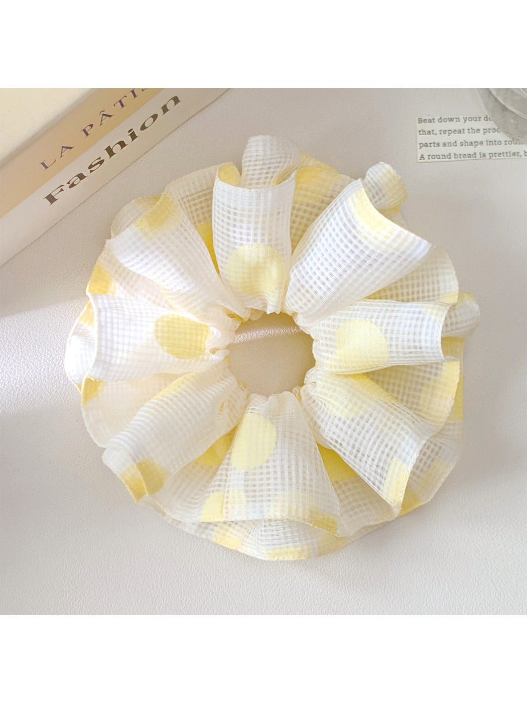 Yellow polka dot scrunchie styled on a wrist as an accessory