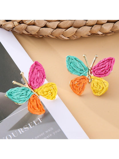 Pair of butterfly drop earrings laid flat on a wooden surface