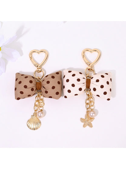 Keypus bow-shaped keychain with white polka dots on a black background