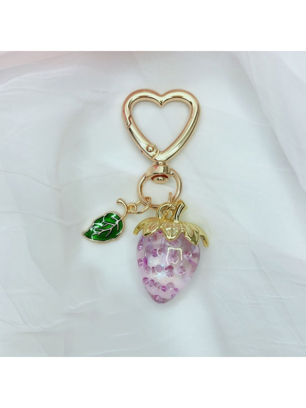 Keypus strawberry charm keychain hanging from a car key on a wooden table