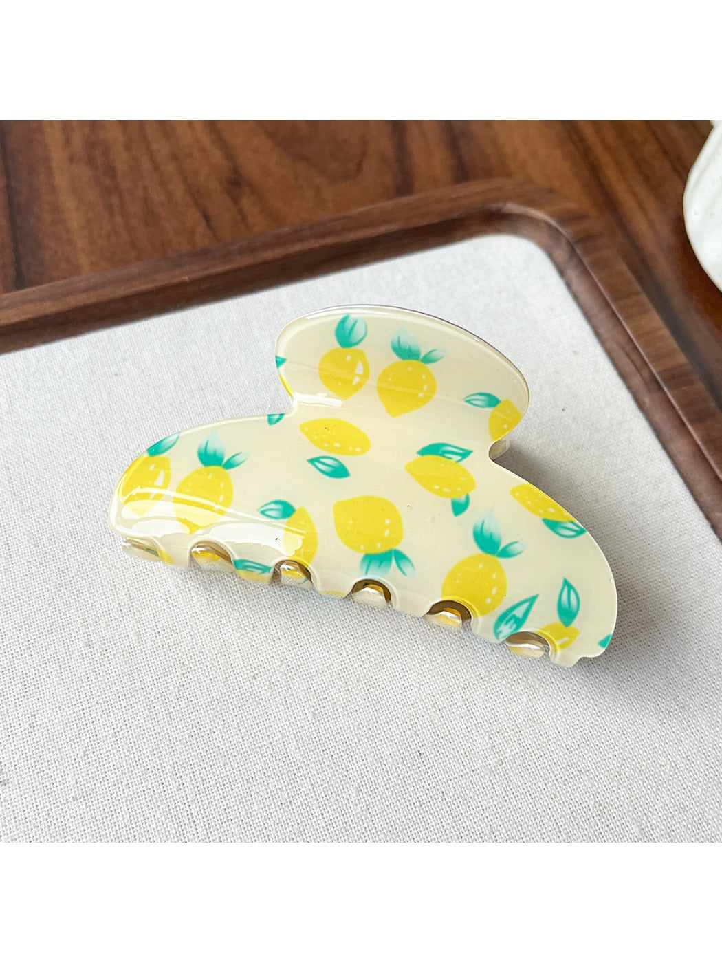 Beau acrylic claw clip resting on white surface with fruit motifs