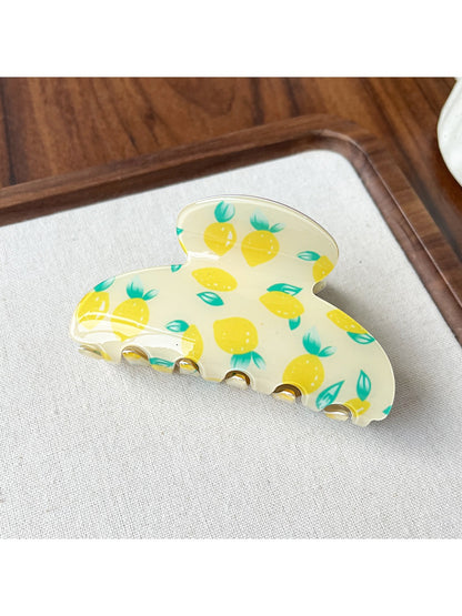 Beau acrylic claw clip resting on white surface with fruit motifs