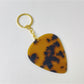 Silver teardrop charm keychain attached to a metal keyring on a dark fabric