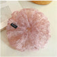 Side view of large pink tulle scrunchie highlighting fabric texture and flowers