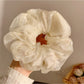 Flat lay of a solid color ruched scrunchie next to casual accessories