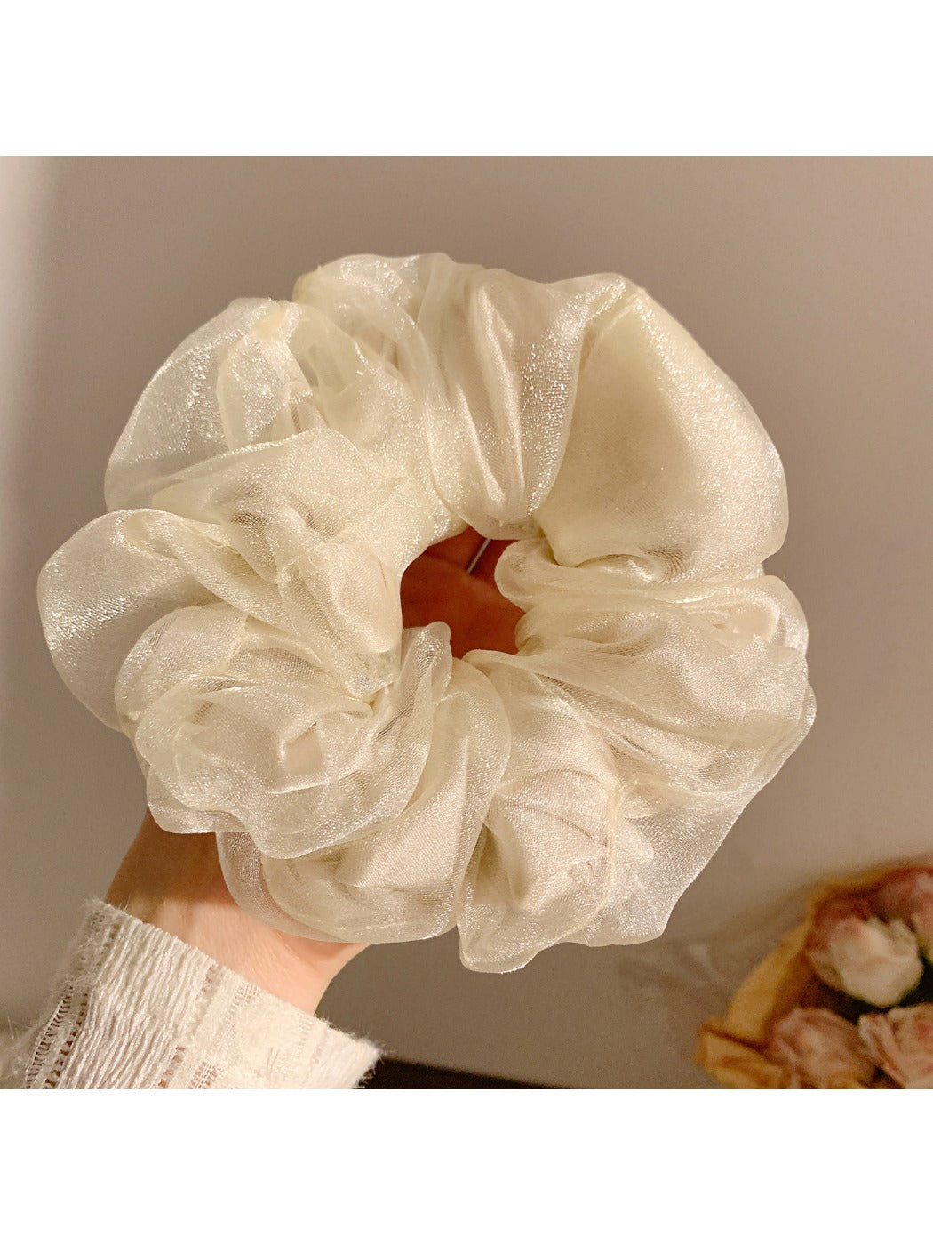 Flat lay of a solid color ruched scrunchie next to casual accessories