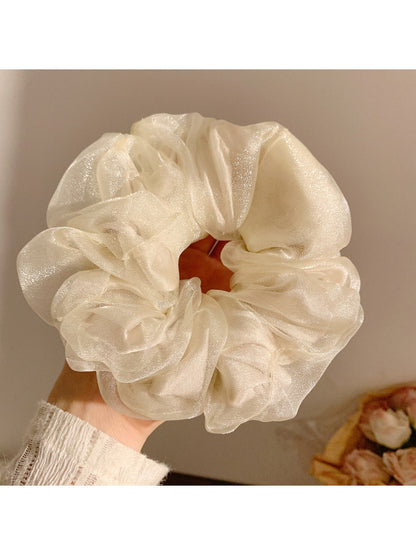 Flat lay of a solid color ruched scrunchie next to casual accessories