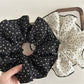 Gifty large floral scrunchie styled on a wrist as an accessory