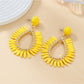 Earedge minimalist oval raffia drop earrings hanging from a white ceramic stand
