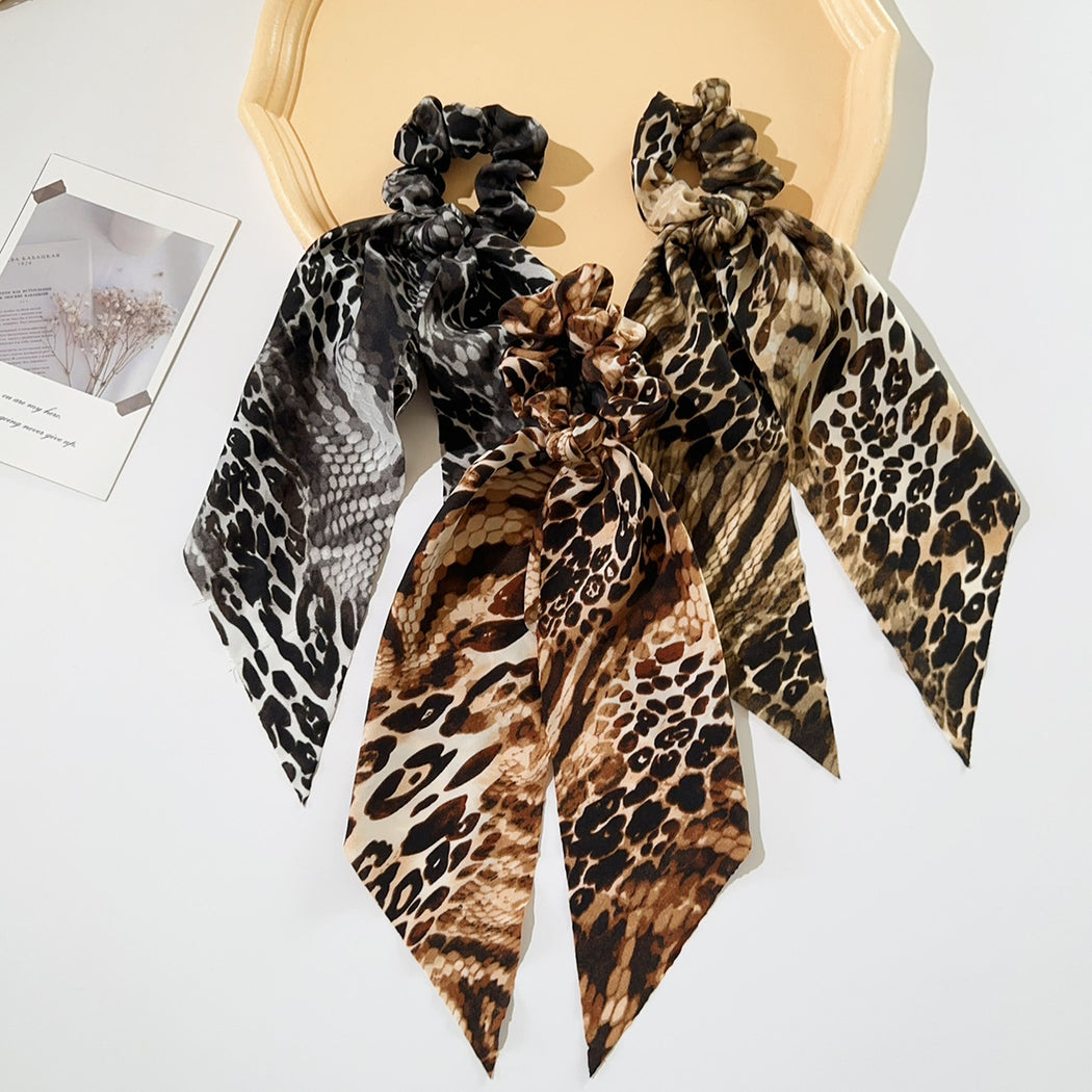 Three snakeskin ribbon bow scrunchies in a display