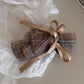 Beau checkered bow hair clip placed next to matching accessories on a flat surface