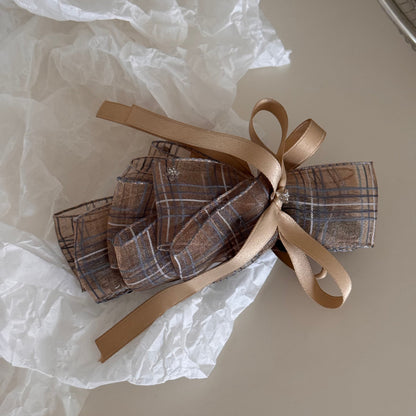 Beau checkered bow hair clip placed next to matching accessories on a flat surface