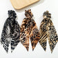 Three snakeskin ribbon bow scrunchies on white background