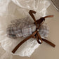 Beau checkered bow hair clip held in hand showing size and detail of the bow