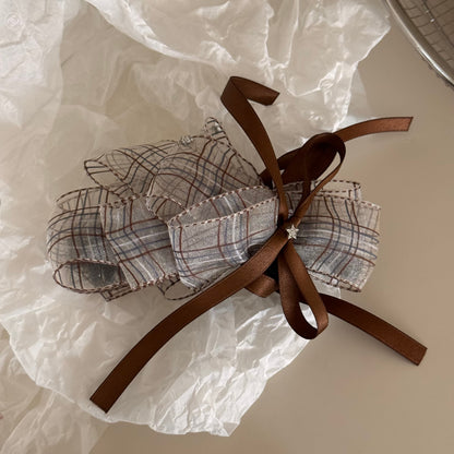 Beau checkered bow hair clip held in hand showing size and detail of the bow