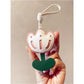 Pink tulip bag charm displayed on a wooden surface