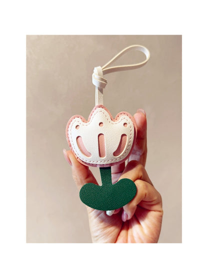 Pink tulip bag charm displayed on a wooden surface