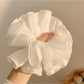 White ruffled scrunchie styled on a model's ponytail
