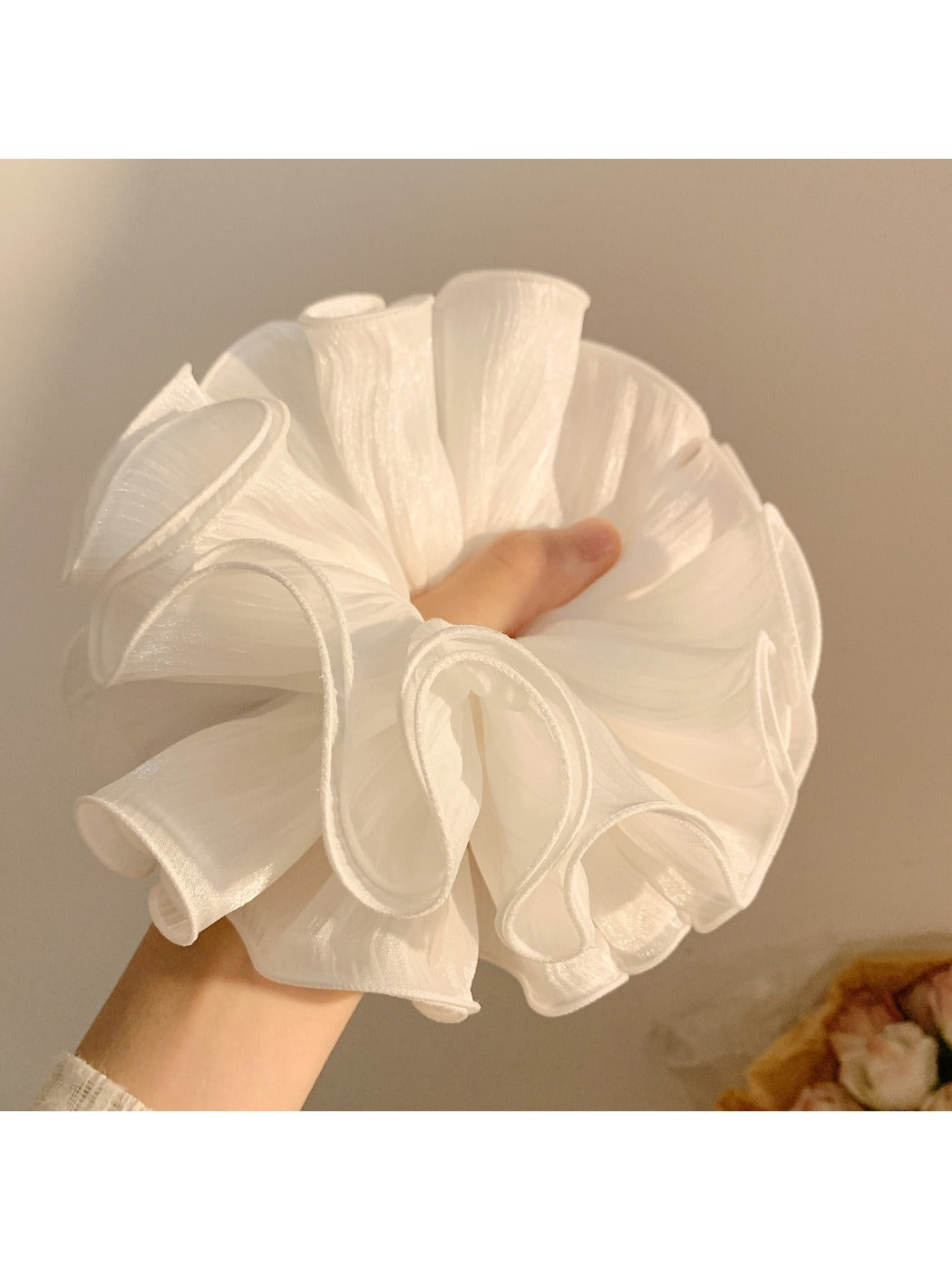 White ruffled scrunchie styled on a model's ponytail