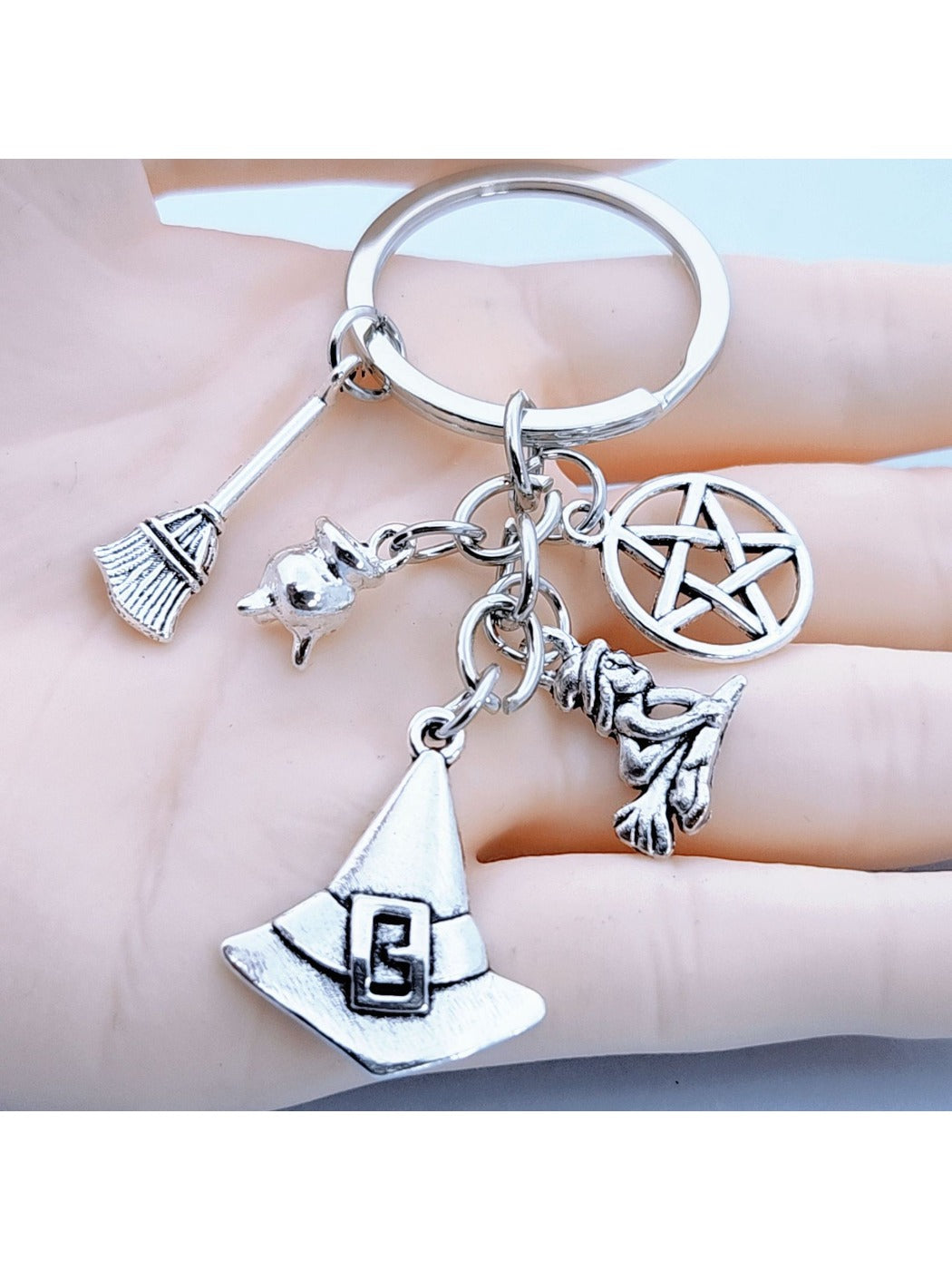 Close-up of silver alloy witch hat keychain with detailed broom charm