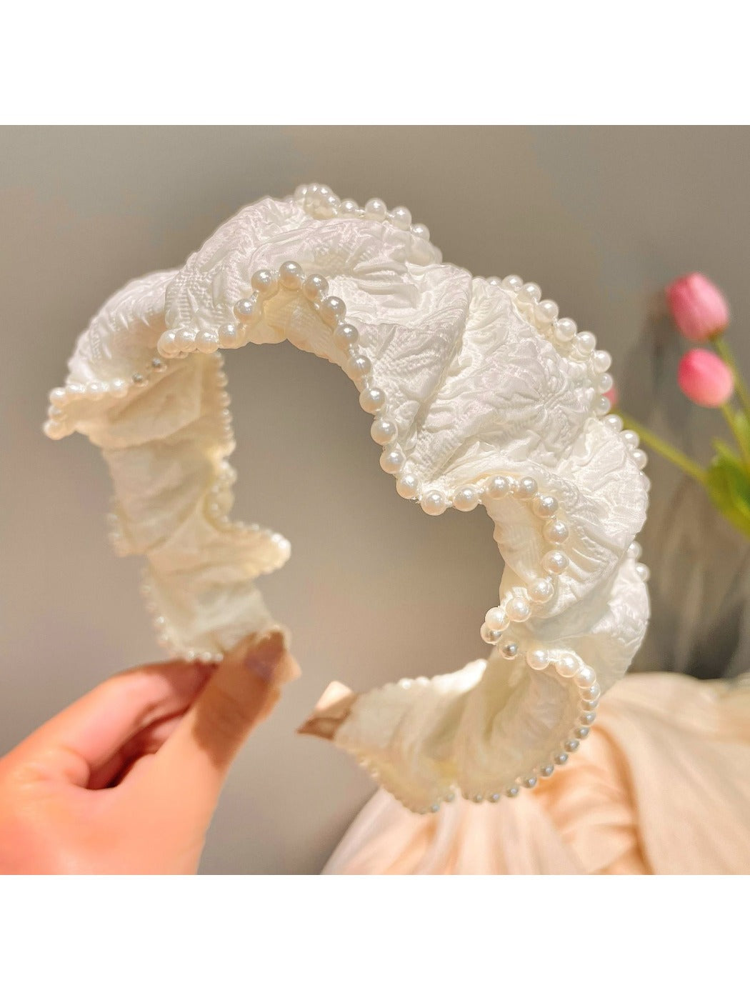 Black fabric headband with a large, intricately beaded bow centerpiece