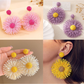 Close-up of colorful floral raffia statement drop earrings on white background