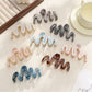 Close-up of Beau elegant wavy hair clip in gold finish on white background