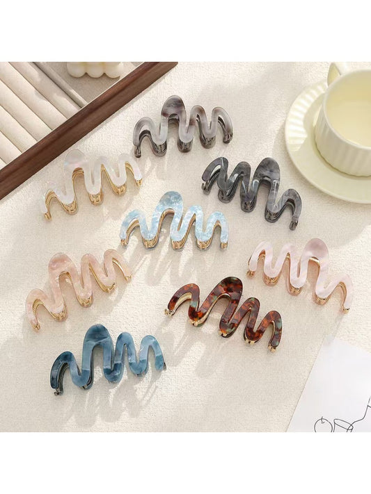 Close-up of Beau elegant wavy hair clip in gold finish on white background