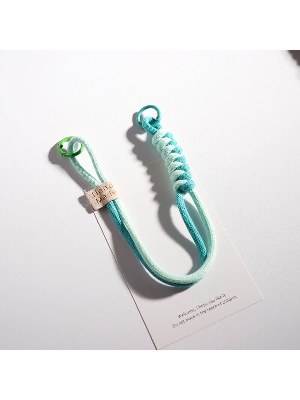 Hand holding a colorful twisted rope keychain with metal ring
