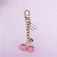 Cherry charm keychain hanging from a bag zipper as a decorative accessory
