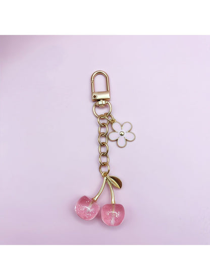 Cherry charm keychain hanging from a bag zipper as a decorative accessory