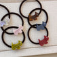 Gifty hair tie featuring a smiling cartoon puppy charm on a black elastic band