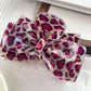 Beau bow-shaped claw clip with leopard print next to green leaves