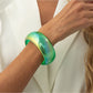 Lovra minimalist colorful bangle bracelet on a reflective surface