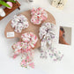 Close-up of Gifty floral scrunchie with ruffled fabric and bow accent in soft pastel colors