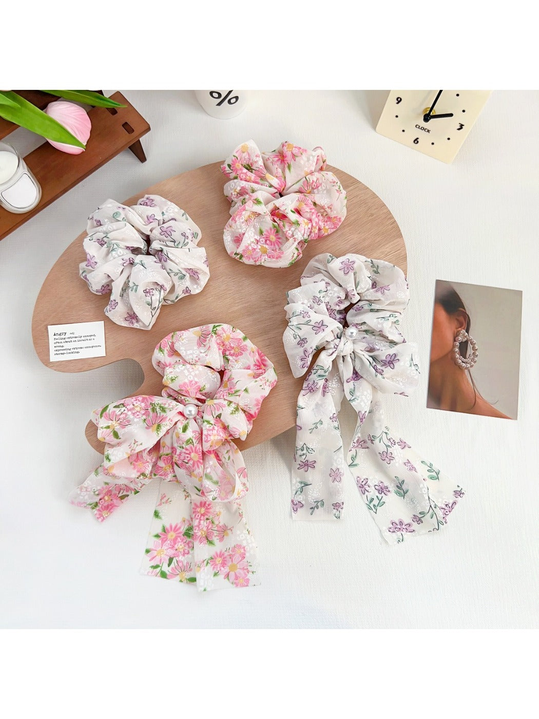 Close-up of Gifty floral scrunchie with ruffled fabric and bow accent in soft pastel colors
