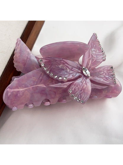 Beau hair claw clip with bright butterfly decorations against a pastel background