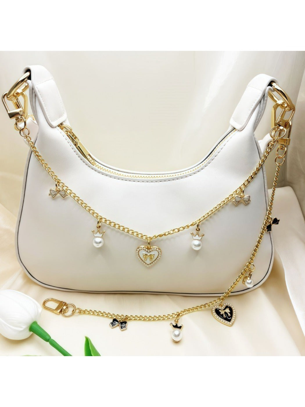 Close-up of gold bow detail on heart pendant bag charm with pink leather background