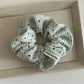 Scrunchie laid flat showing circular cutout design and soft fabric folds