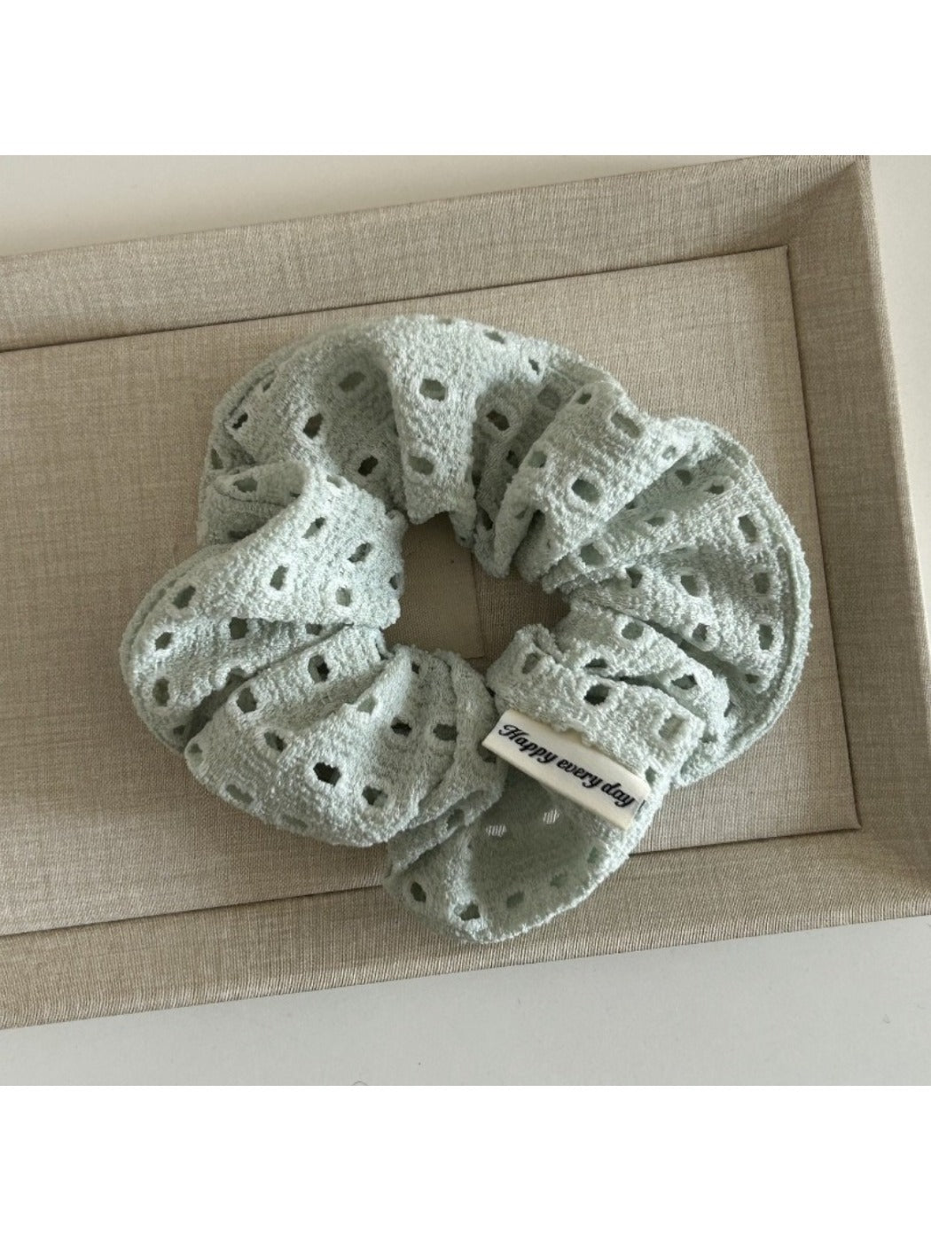 Scrunchie laid flat showing circular cutout design and soft fabric folds