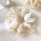 White tulle scrunchie with ruffled edges shown from a side angle